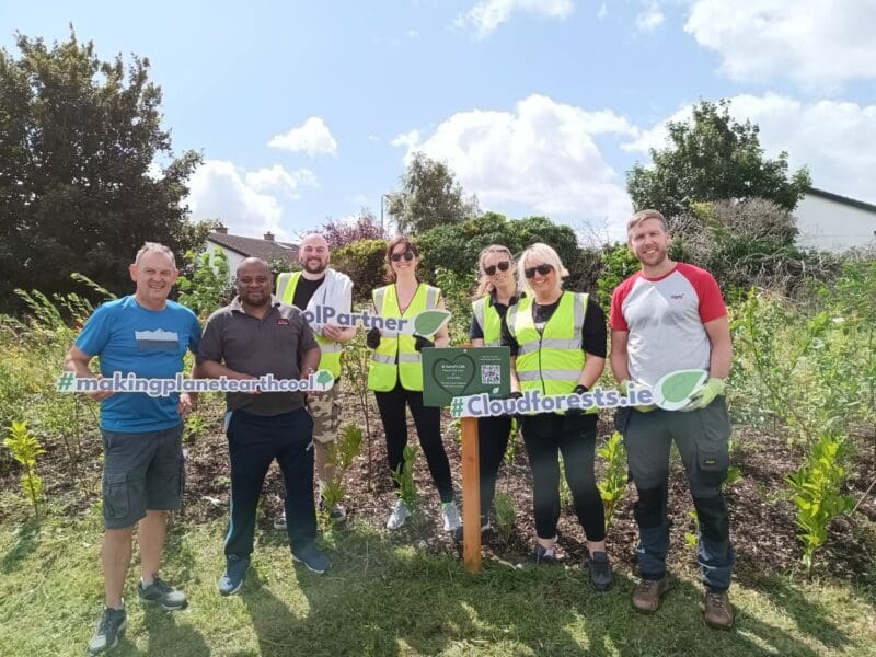 Member First Credit Union team standing at Cloudforests' Urban Forest Maintenance Day at St David's College in Artane holding hashtag signs that reads #MakingPlanetEarthCoolAgain, #CoolPartner #Cloudforests.ie